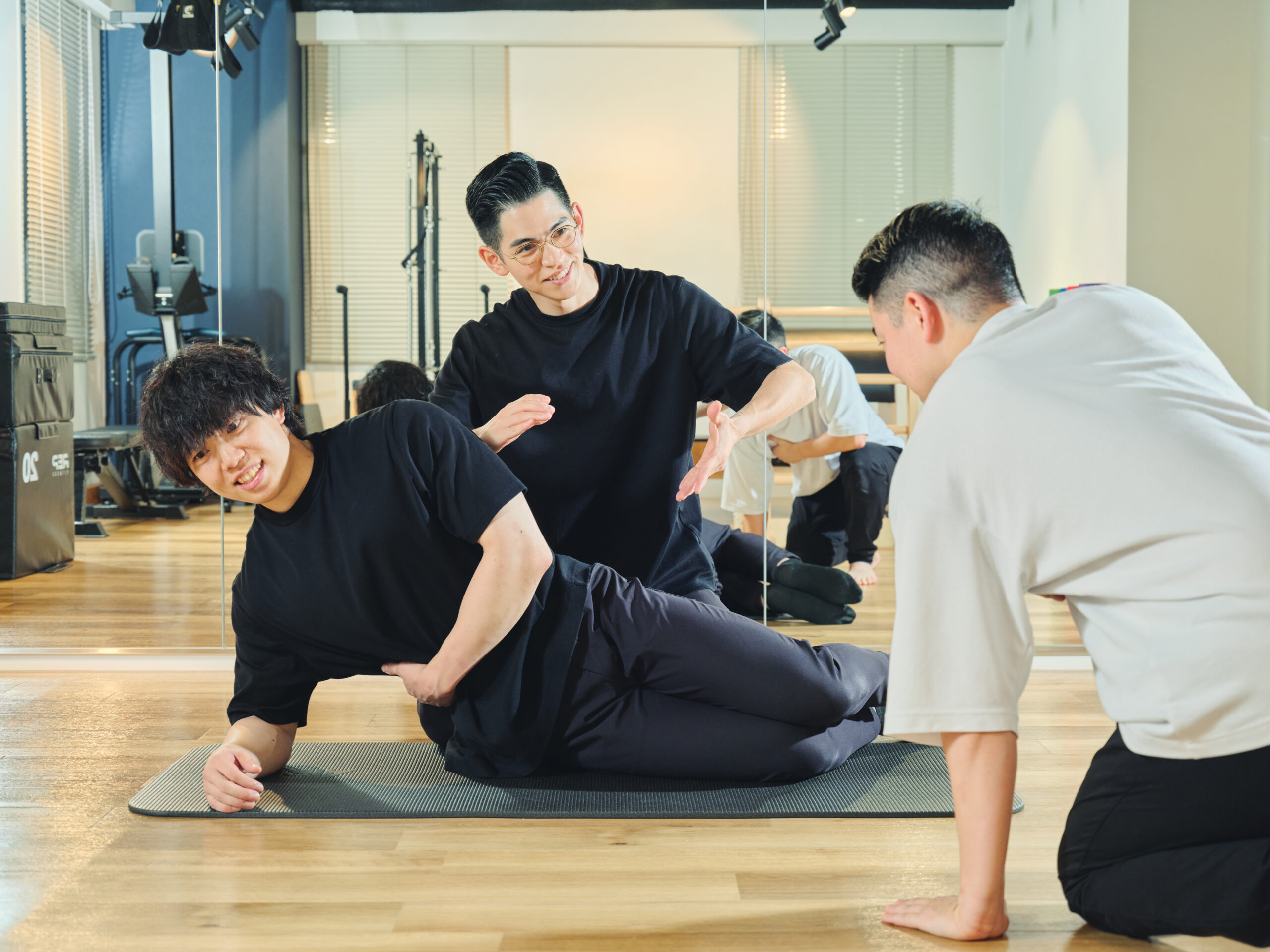トレーナー同士が指導し合いながらマットエクササイズを行う様子